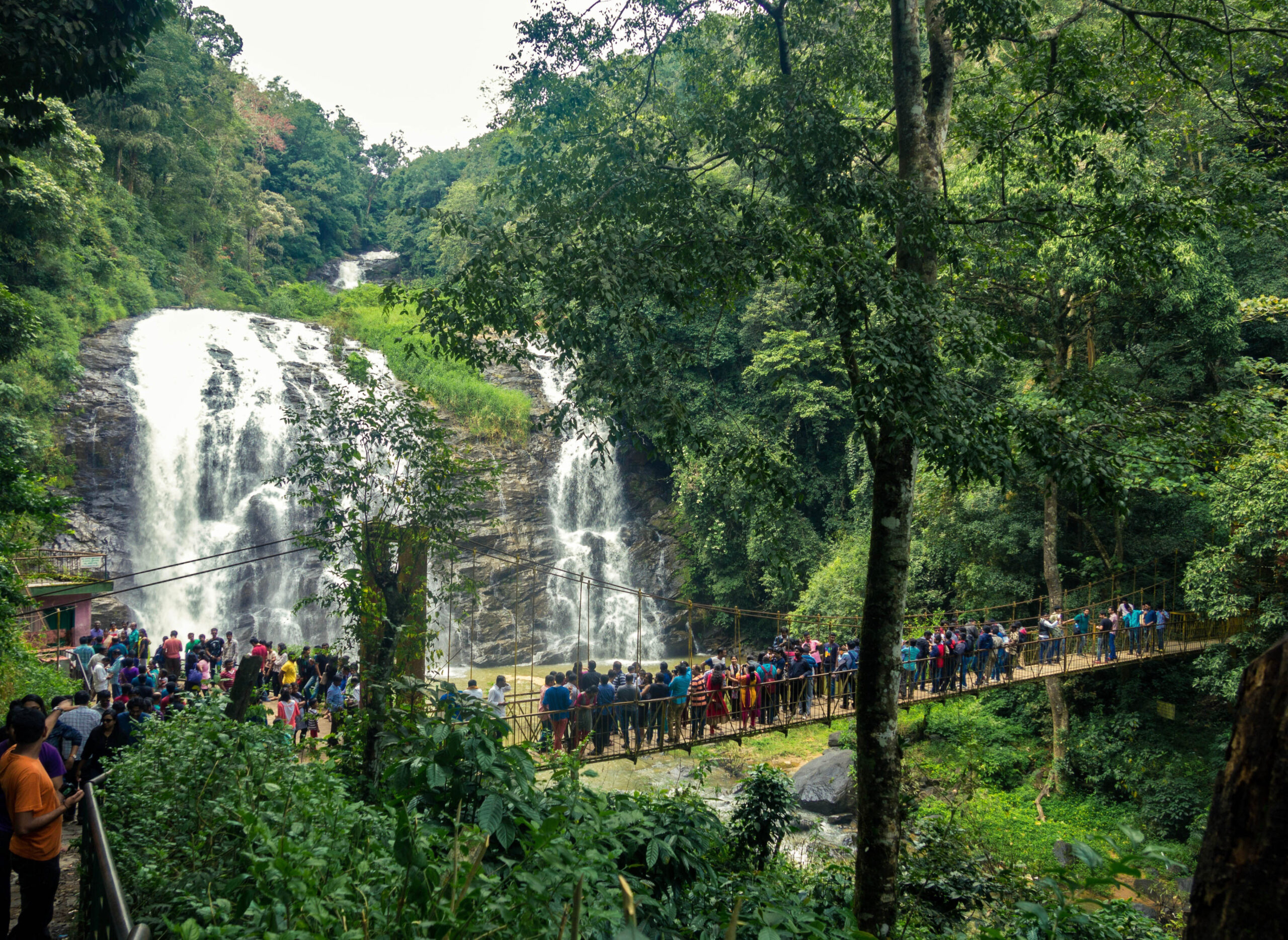 View of Abbey Falls Coorg with people flocking the hanging bridge.